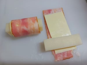 焼く前の細く切ったお餅にベーコンとチーズを巻いている写真