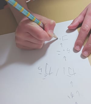 白い紙にひらがなの練習でしりとりを鉛筆で書いている子どもの手の写真
