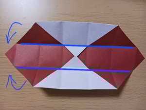 4つの折り上げた角の左右の角を元に戻して、上下に折るように青い線と矢印が書かれた写真