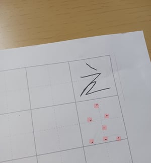 上のマスの中に「え」を描いた文字と、下のマスの中に「え」の文字のガイドで目印の点の印が書かれている写真