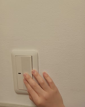 電気のスイッチを押している子どもの手の写真