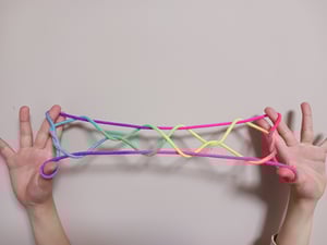 カラフルな紐のあやとりではしごを作っている写真