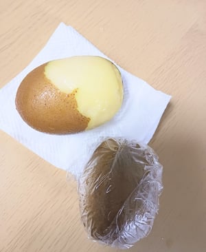 半分まで皮をむいたキウイと、ラップで丸ごと包んだキウイの写真