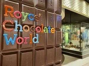 空港内のロイズ工場前にある、ロイズチョコレートワールドとカラフルな文字で書かれた板チョコの壁の写真