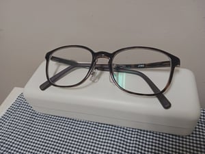 眼鏡ケースの上に乗った、太縁の眼鏡の写真